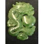 A carved jade amulet talisman, the panel depicting a coiled dragon around a heart. (1.5in)