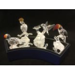 A collection of Swarovski birds on mirrored display stand - a cockatoo with yellow plume, a parakeet