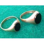 Two hallmarked gold signet rings, each with oval black stones set within the tapering bands. (2)