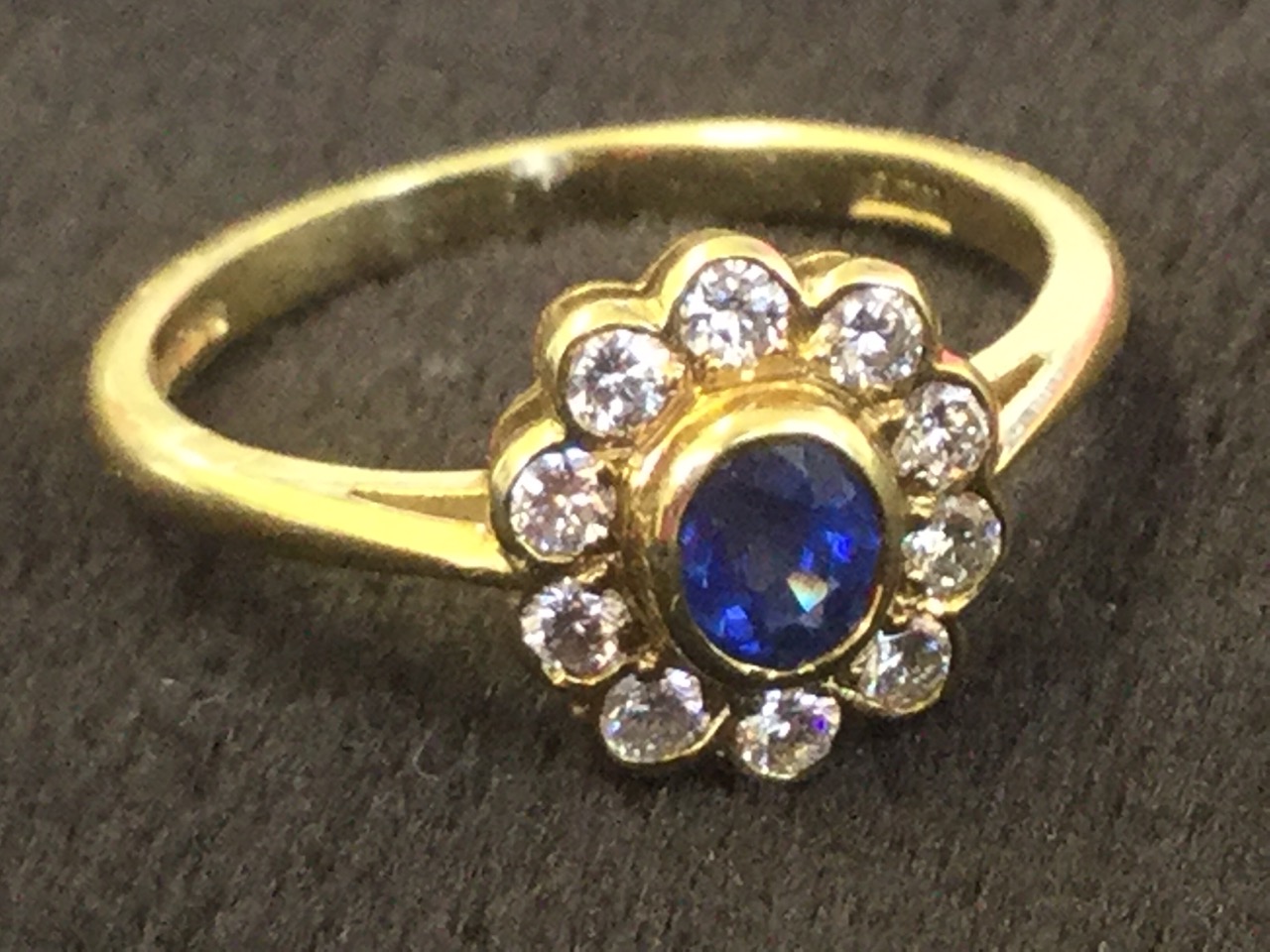 A 18ct yellow gold sapphire & diamond cluster ring, the oval bezel set sapphire framed by a border - Image 3 of 3