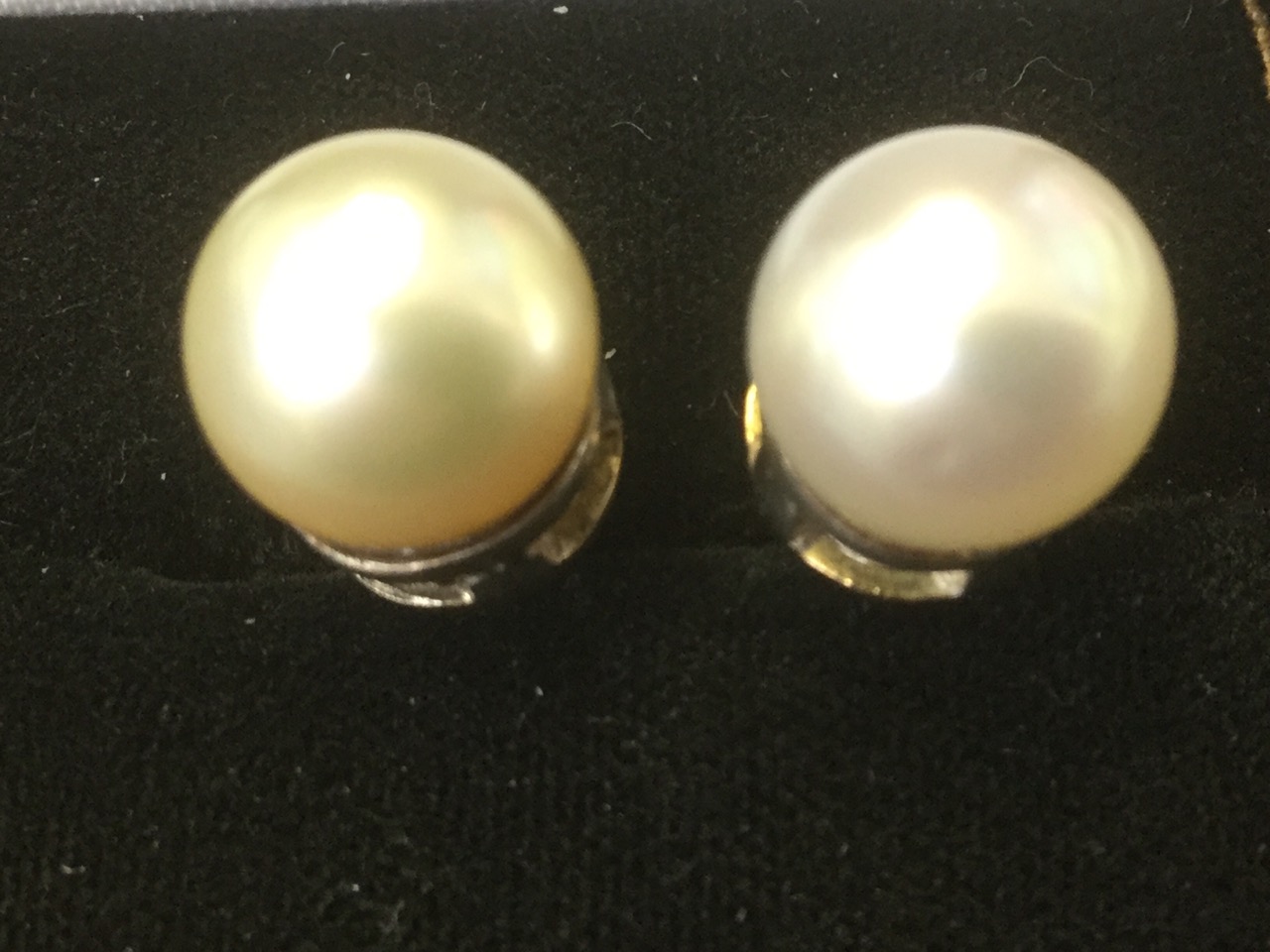 A pair of large quarter inch pearl earrings, the iridescent pearls on a pierced collar, with