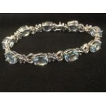 An 18ct white gold aquamarine & diamond bracelet, the nine oval aquamarine stones of fifteen carats,