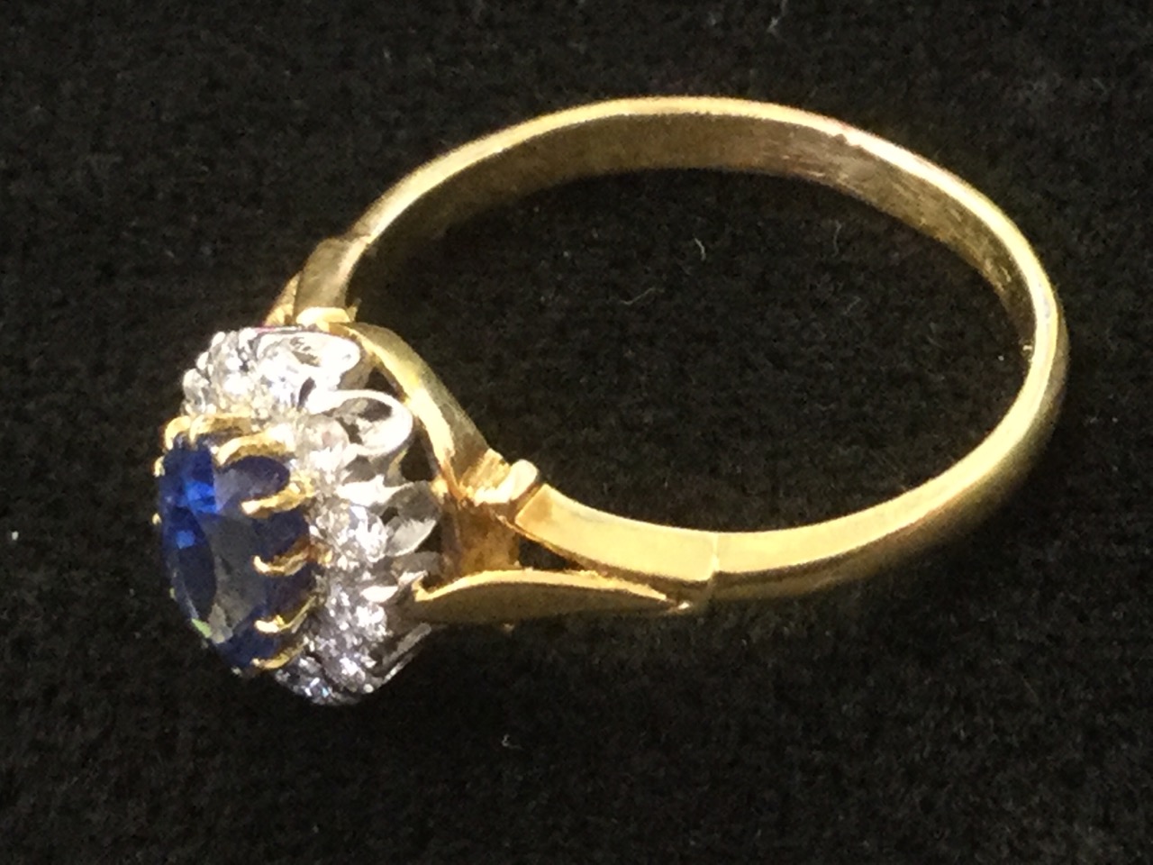 A sapphire & diamond ring, the oval claw set sapphire of over a carat, framed by twelve diamonds - Image 2 of 3