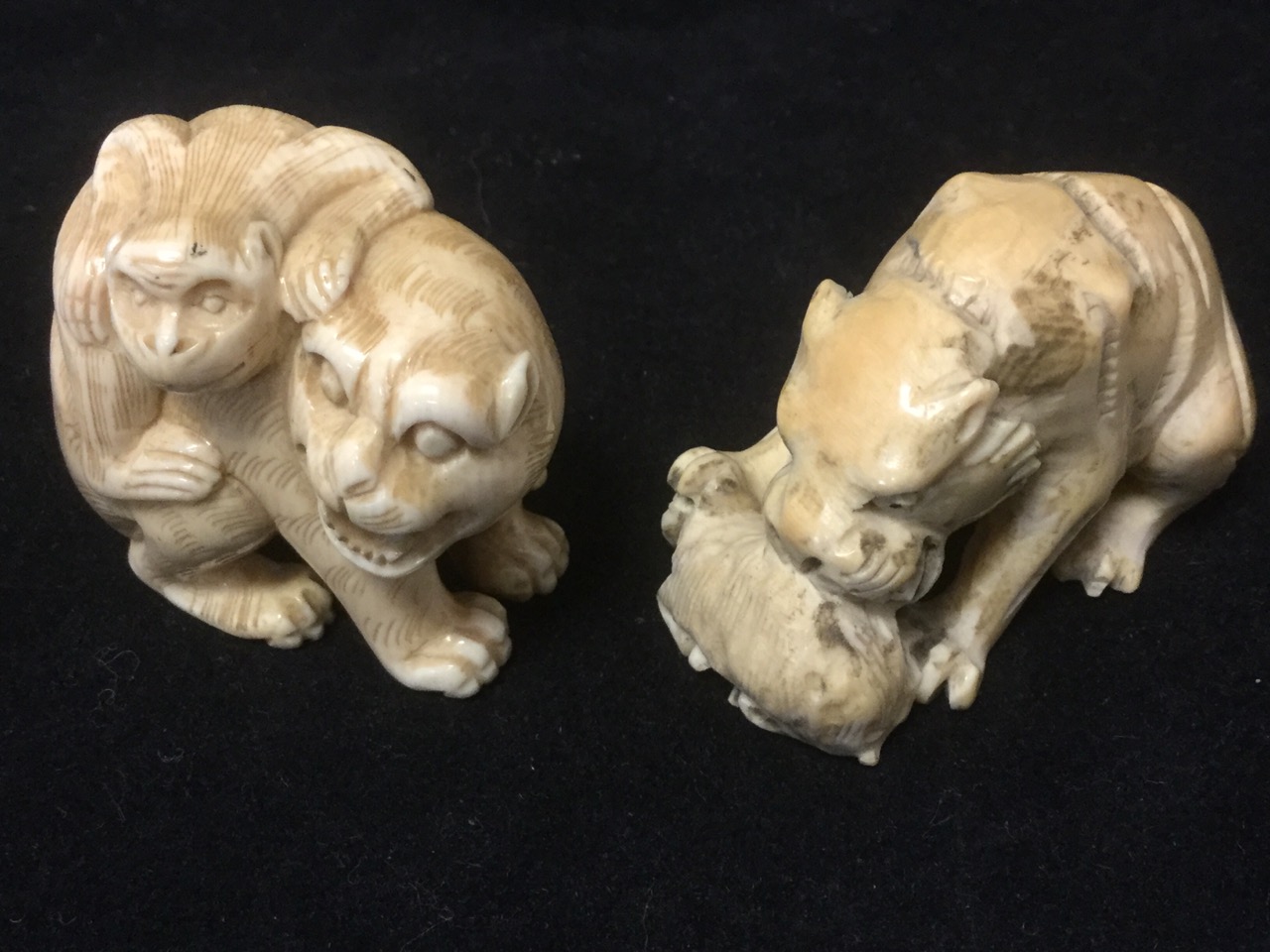 A carved ivory netsuke of a cat with monkey on its back; and another carved as a lion eating its