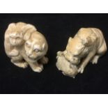 A carved ivory netsuke of a cat with monkey on its back; and another carved as a lion eating its