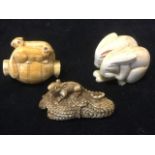 A carved ivory netsuke with two squirrels on a barrel; another carved as a pair of squatting