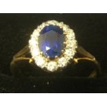A sapphire & diamond ring, the oval claw set sapphire of over a carat, framed by twelve diamonds