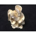 A carved ivory netsuke depicting a bearded immortal with gourd & rat, the cloaked figure with two