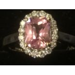 An 18ct gold radiant cut pink sapphire & diamond cluster ring, the claw set rectangular sapphire