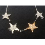 A 14ct two-tone gold diamond star necklace, the diamonds pave set within the stars, mounted on a
