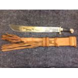 A South American machete, the blade with engraved decoration having lionhead terminal, the leather