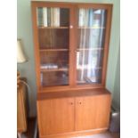 A 70s teak bookcase, with pair of glazed doors enclosing adjustable shelves, above a base with