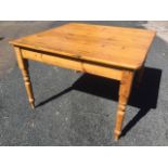 A Victorian square pine kitchen table, raised on turned legs.