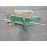 A wood wheelbarrow with angled sides and shaped handles, having rubber tyre.
