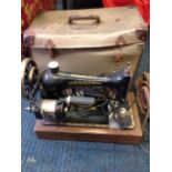 A cased Singer sewing machine with gilt decoration, on an oak plinth.