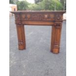 An oak breakfront chimneypiece, having moulded cornice above carved harebell swag frieze flanked