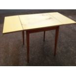 A 60s formica topped drop-leaf dining table, supported on rectangular rounded tapering legs.