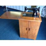 A walnut cased Singer sewing machine, the cabinet with flip-over-top above cupboard with two