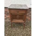 A marble topped oak bedside cabinet, with drawer above panelled cupboard, raised on turned