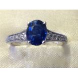 An 18ct gold sapphire & diamond ring, the claw set oval sapphire of one carat, framed by tapering