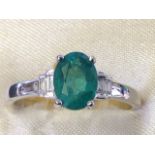 A hallmarked 18ct white gold oval emerald & diamond ring, the claw set emerald of over three-