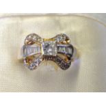 A 14ct gold diamond bow set ring, with stones both baguette & brilliant cut, centred by a square