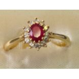 An 18ct rose gold ruby & diamond cluster ring, the oval set ruby framed by a flowerhead border of