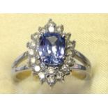 An 18ct gold sapphire & diamond cluster ring, the oval claw set sapphire framed by eighteen