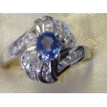 An 18ct white gold sapphire & diamond 'swirl' set ring, the central oval claw set sapphire above