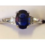 An 18ct gold sapphire & diamond ring, the oval claw set sapphire of over a carat, with graduated
