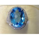 An 18ct gold blue topaz & diamond cluster ring, the large oval topaz of over thirteen carats, framed