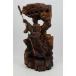 Chinese carved figure of Guan Yu, carved in high relief, carrying guandao on rocky plinth,