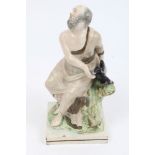 Early 19th century Staffordshire pearlware figure of Elijah and the raven seated on a tree stump,