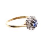 Sapphire and diamond flower-head cluster ring with a circular mixed cut blue sapphire surrounded by