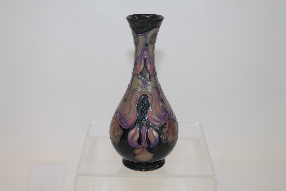 Moorcroft pottery vase decorated with purple flowers on dark green ground, signed on base,