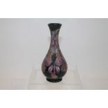 Moorcroft pottery vase decorated with purple flowers on dark green ground, signed on base,