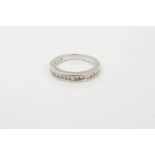 Diamond eternity ring with seventeen princess cut diamonds in channel setting, stamped 14K.