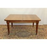 Edwardian honey oak extending dining table, the rectangular top with canted angles,