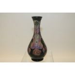 Moorcroft pottery vase decorated with purple flowers on dark green ground, signed on base,