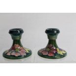 Pair of Moorcroft pottery Hibiscus pattern squat candlesticks on green ground