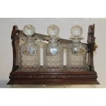 Edwardian tantalus with plated handle and three cut glass decanters with silver spirit labels