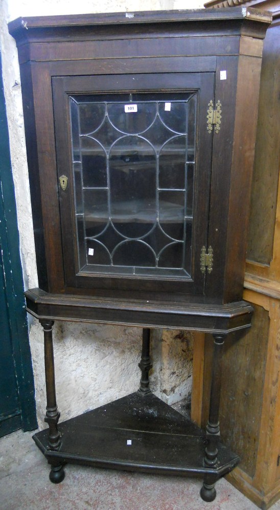 A 34" 19th Century oak corner cabinet on stand, with shelves enclosed by a leaded glazed panel door,