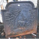 A cast iron dome topped fire back depicting a stag in castle grounds with hunting paraphernalia