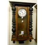 A walnut and ebonised cased Vienna style wall clock with visible pendulum and flanking half column