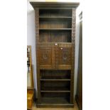 A 36" carved oak bookcase with moulded cornice, six open shelves and central panelled cupboard