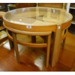 A 32 1/2" diameter retro glass topped table, with three nesting elliptical tea tables