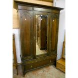 A 4' 6" early 20th Century stained oak wardrobe with hanging space enclosed by a mirror panel,