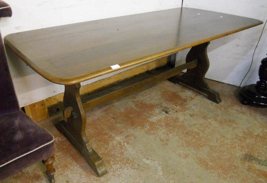 A 6' Ercol style refectory dining table with moulded edge, set on shaped standard ends with pegged