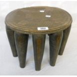 A 12 1/2" diameter African tribal carved hardwood stool with incised decoration and multiple legs