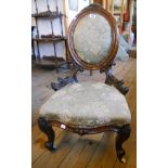 A high Victorian mahogany framed nursing chair with oval upholstered back panel and seat, carved